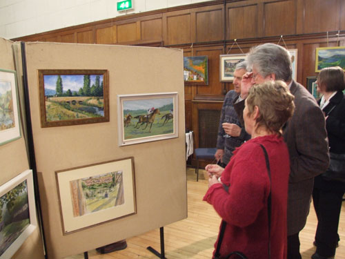 Visitors admiring paintings at the exhibition in the Soper Hall