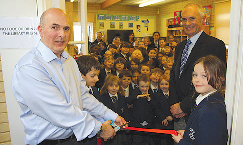 Ian MacDonald cuts the ribbon to the new library watched by headteacher Mike Donald and pupils of Warlingham Park School.