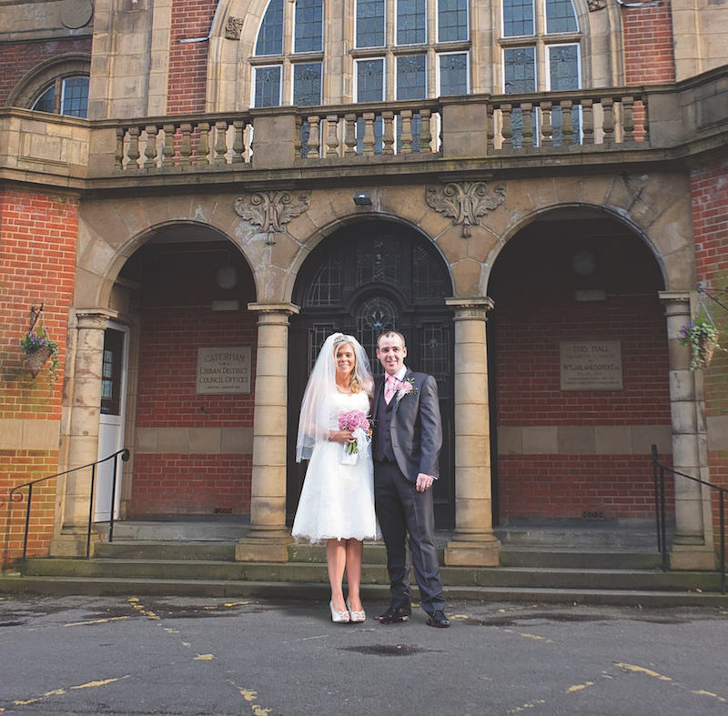 A bride and groom outside the grand entrance to the Soper Hall